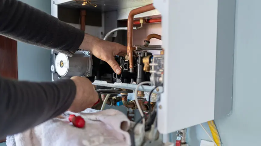 A technician is repairing a water heater system.