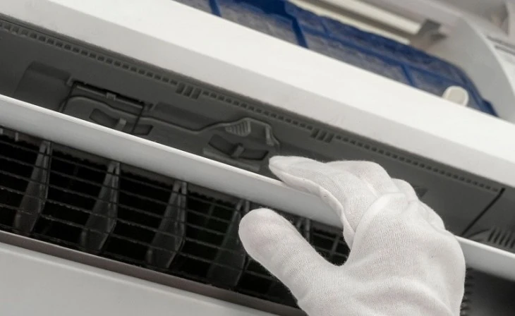 The image shows an air conditioner being maintained