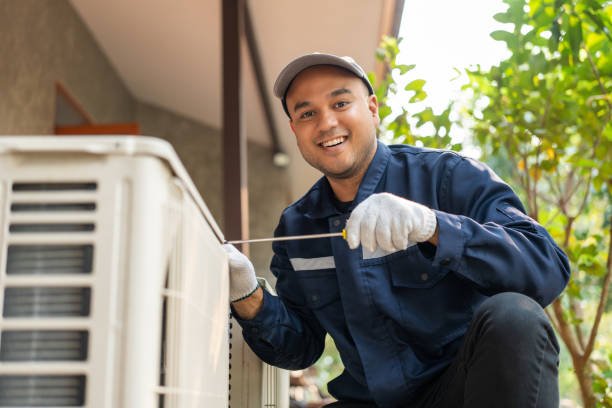 Smiling HVAC technician servicing an air conditioner